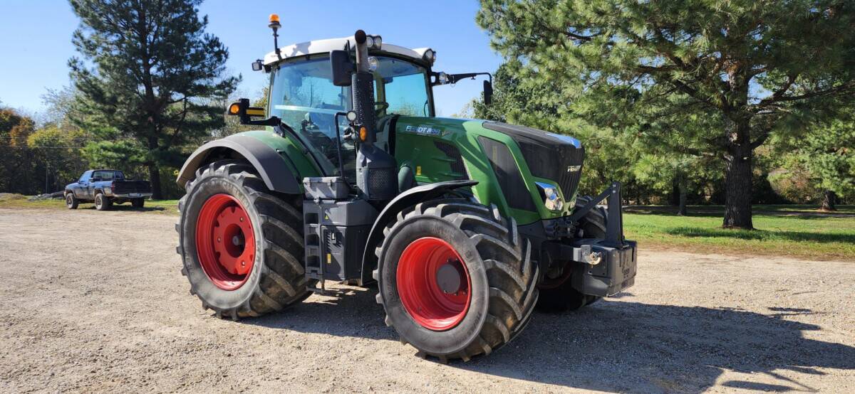 Green and black John Deere tractor with red wheels, outdoor setting, no visible year or model.