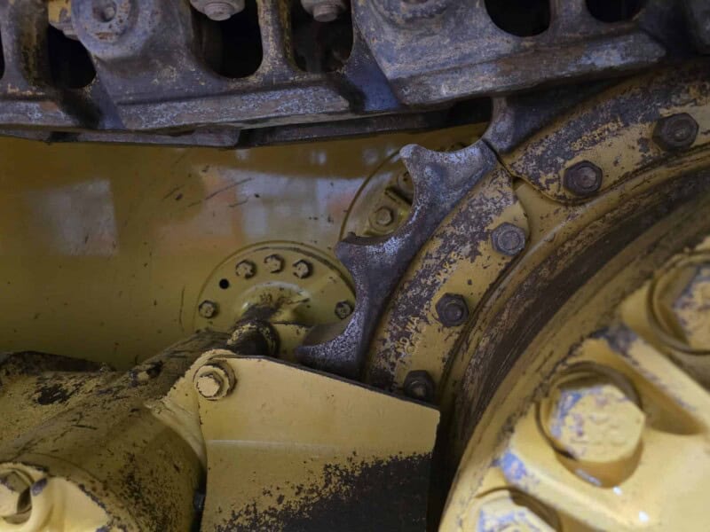 Track-type tractor with yellow and black components, showing detailed undercarriage and track system.