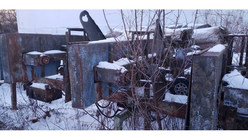 Old, rusty farm equipment and machinery in a snowy outdoor setting.