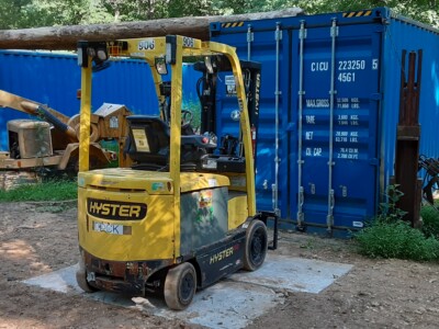 Yellow Hyster E50XM forklift with mast and forks, outdoor setting with blue shipping container.