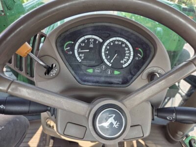 John Deere tractor dashboard with gauges and controls, green exterior visible.