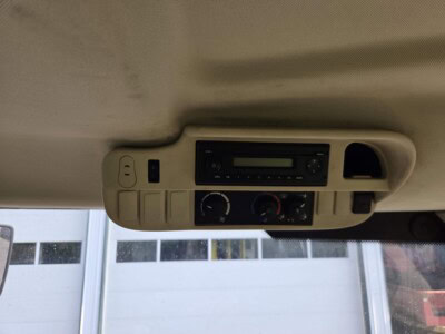 Vehicle interior ceiling with radio and climate controls in a John Deere 6125R tractor.