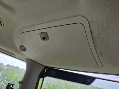 View of the tractor cab ceiling with a storage compartment and interior light.