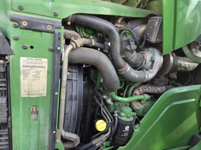 John Deere 6125R engine with visible hoses and components in green and black.