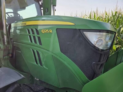 John Deere 6125R tractor with green body and black grille, front view in a field.