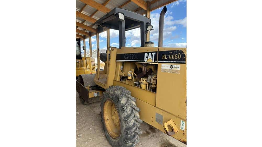 CAT HL0050 compact wheel loader from 2021 under a wooden shelter with blue sky background.
