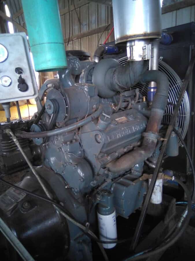 Industrial diesel engine with various hoses and components in a workshop setting.