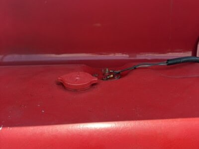 Red Massey Ferguson 50 tractor fuel cap and hose on red body.