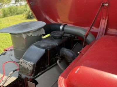 Close-up of engine compartment on 1963 Massey Ferguson 50 tractor with red body and black engine parts.