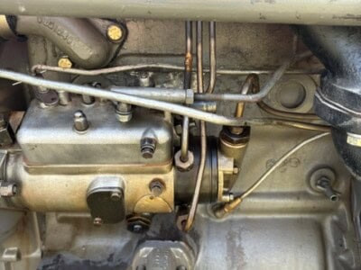 Close-up of a vintage tractor engine with visible metal components and hoses.