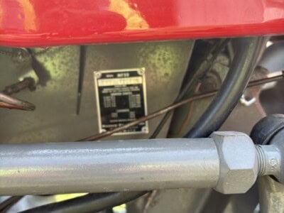 Close-up of Massey Ferguson 50 tractor engine and hydraulic parts, red body with Ferguson System label.