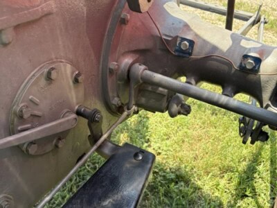 Close-up of vintage tractor's steering and control components, showing metal parts and foot pedal.