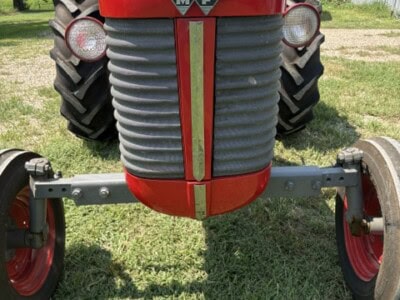 Red Massey Ferguson 50 tractor with gray grille and large rear tires on grassy field.