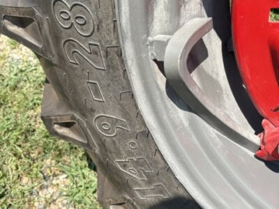 Close-up of tractor tire with visible size 11.2-28 and tread pattern.