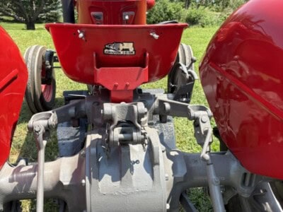 Front view of a vintage red Massey Ferguson tractor with steering wheel and engine components visible.