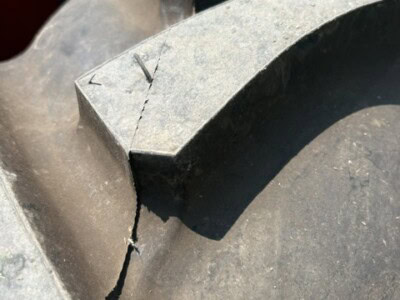 Close-up of a cracked and worn heavy equipment tire showing damage and aging signs.