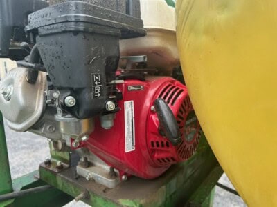 Red Honda GX160 engine with pull start and black fuel tank for agricultural sprayer.
