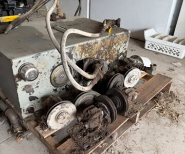 Old industrial diesel power unit with rust, dirt, and worn components on a wooden pallet.