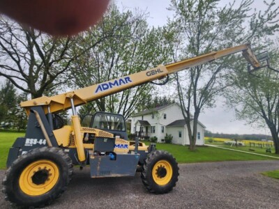 2017 Gehl RS8-44 telehandler with ADMAR branding, yellow and black, parked outdoors near trees and residential buildings.