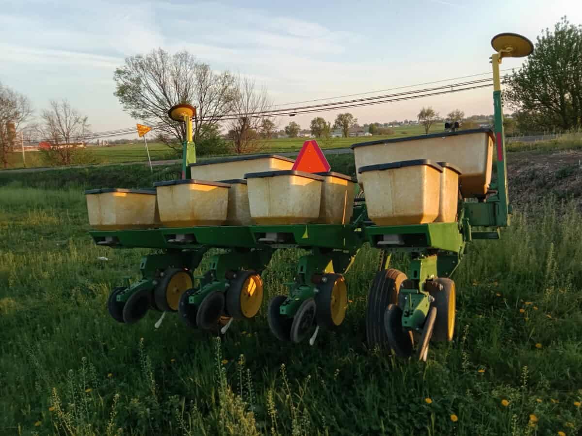 Vintage green and yellow agricultural planter with seed hoppers, outdoor setting, no visible year or model.