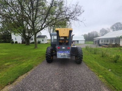 Heavy-duty yellow and black Gehl RS8-44 skid steer loader on a gravel path in a rural setting.