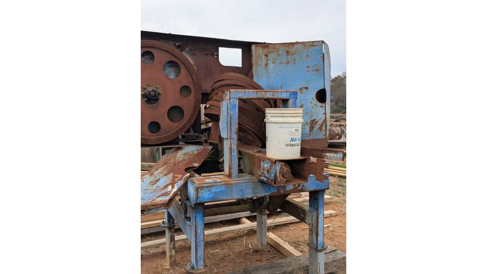 Old blue and rusted industrial machine with a white bucket, no visible brand or model, outdoors on a dirt surface.