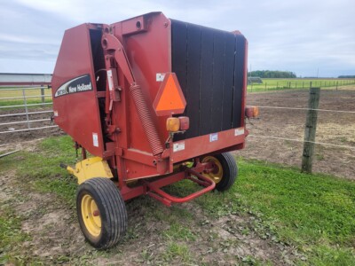 New Holland round baler, red and black, for hay and straw baling.