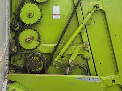 Close-up of green agricultural equipment with gears and chains, no visible year or model.