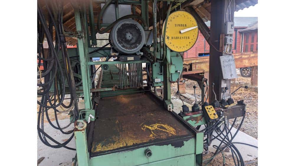Heavy-duty green logging sawmill with control panel and hydraulic system for timber processing.