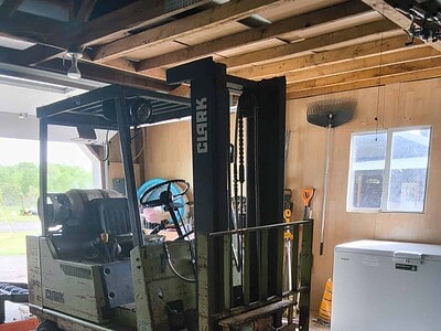Forklift with 3000 lb capacity, black and green, inside a wooden workshop.