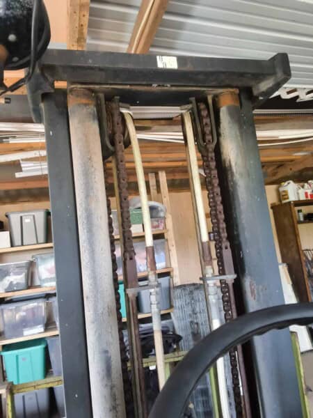 Forklift with rusted chains and metal frame, designed for material handling in industrial settings.
