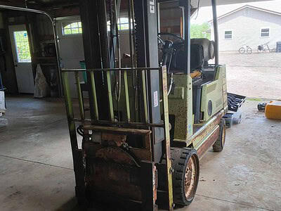 Electric forklift with 3000 lb capacity, green and black color, in a garage setting.