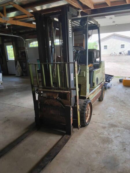 Electric forklift with 3000 lb capacity, green and black color, in a garage setting.