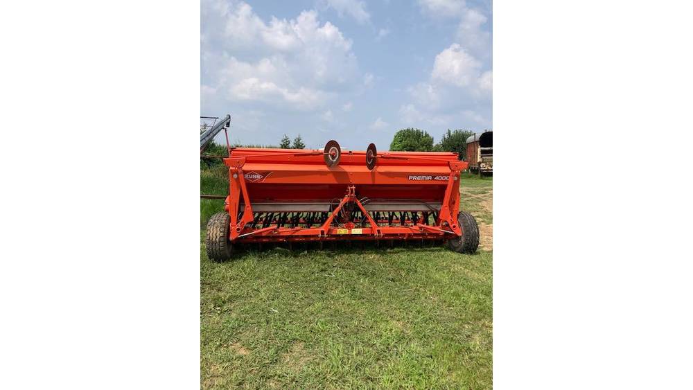 Red 2020 John Deere rotary tiller attachment for tractors, outdoor equipment, on grassy field under blue sky.