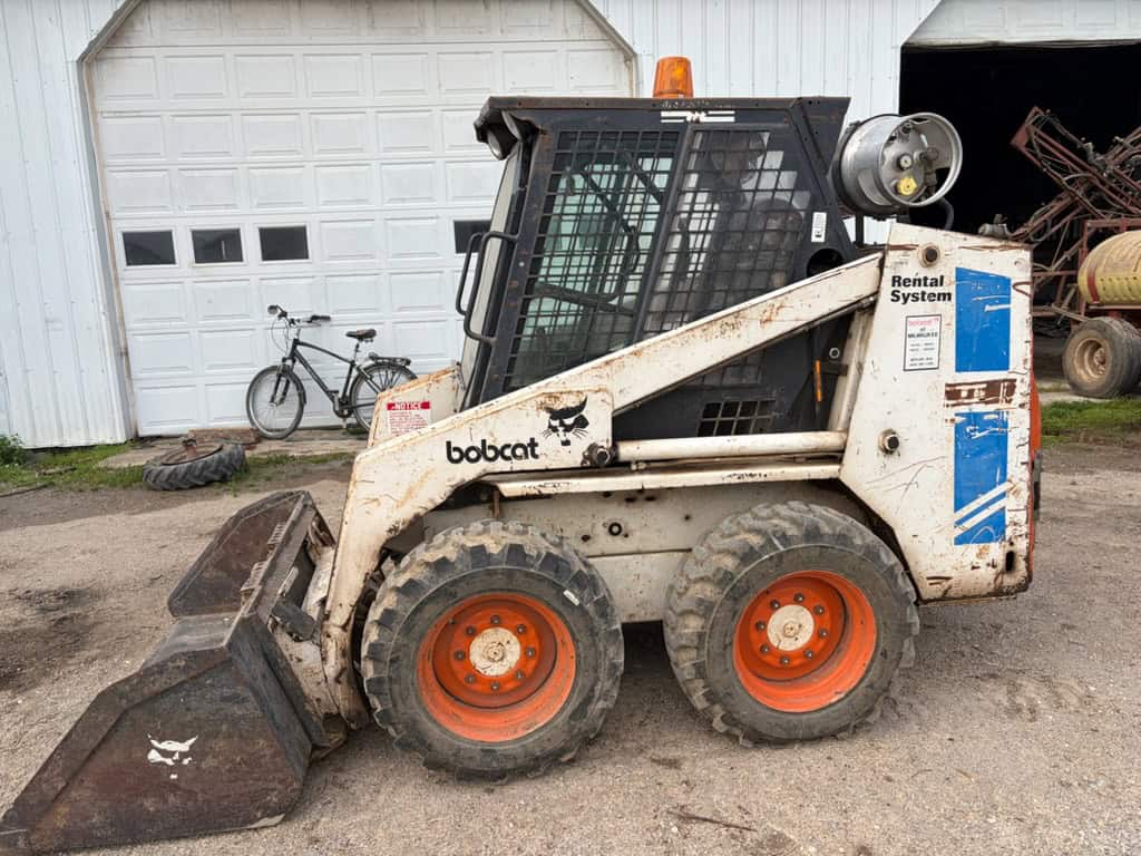 Compact Bobcat skid-steer loader with bucket attachment, white and black, 2010 model, suitable for construction and landscapi.