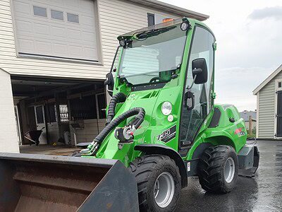Green compact loader with front bucket, ideal for construction and landscaping projects.