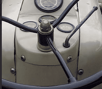 Close-up of vintage tractor dashboard with steering wheel and gauges.