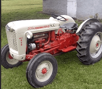 Vintage 1950s Farmall A tractor with white and red paint, used for agricultural tasks, parked on grass near a house.