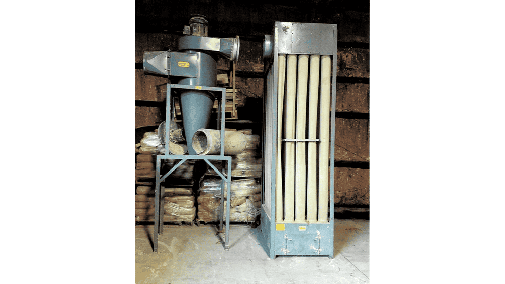 Industrial dust collector system with large filter unit and cyclone separator, used for air purification in manufacturing fac.