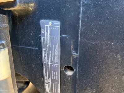 Close-up of a blue tractor with a metal identification plate on the side.
