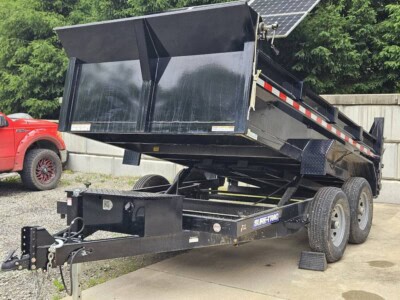 Heavy-duty black dump trailer with hydraulic lift, dual axles, and 2023 model year, ideal for construction and landscaping ta.