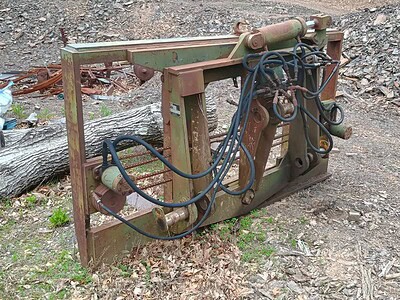 Heavy-duty hydraulic log splitter attachment on rough terrain, no visible branding or model info.