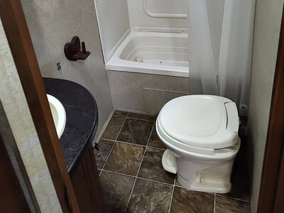 Compact bathroom with shower, toilet, and sink in a small RV or camper.