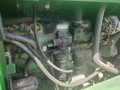 Close-up of a green John Deere tractor engine with filters and hoses.