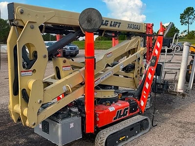 Compact JLG lift with extendable boom and tracked base, suitable for construction and maintenance tasks.