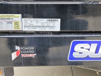 The image contains labels and manufacturer information on a piece of equipment, likely a trailer or similar machinery, with v.