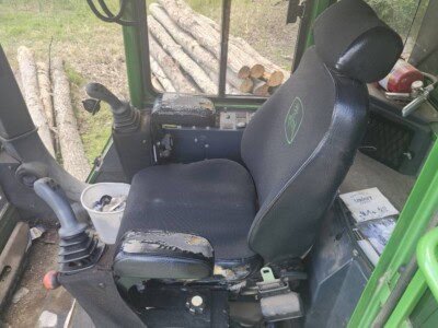 John Deere tractor seat with visible wear and tear, inside the cab.