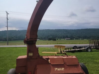 Red New Holland 782 wood chipper with large discharge chute and wheels.
