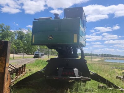 John Deere 2020 forestry mulcher attachment on a tracked vehicle in a grassy field.