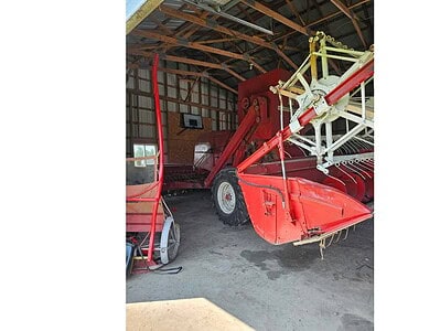 Red John Deere 2015 rotary hay rake inside a barn for agricultural use.